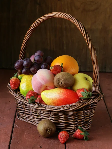 Cesta de vime de natureza morta com fruto em uma mesa de madeira — Fotografia de Stock