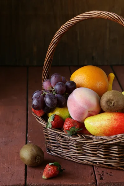 Cesta de vime de natureza morta com fruto em uma mesa de madeira — Fotografia de Stock