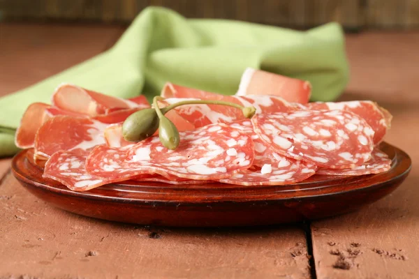 Sliced dried sausage meat (ham, prosciutto, salami) served on a wooden board — Stock Photo, Image