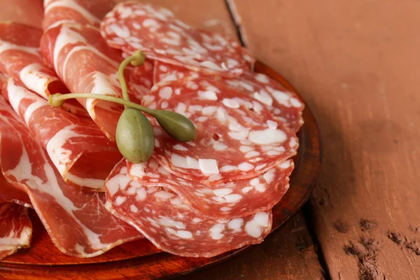 Sliced dried sausage meat (ham, prosciutto, salami) served on a wooden board — Stock Photo, Image