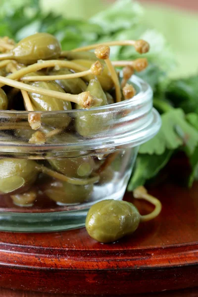 Alcaparras en escabeche en un tazón sobre una mesa de madera — Foto de Stock