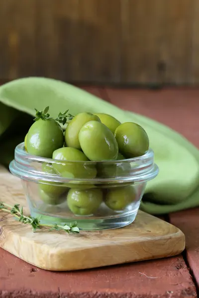 Groene gemarineerde olijven in kom op een houten tafel — Stockfoto