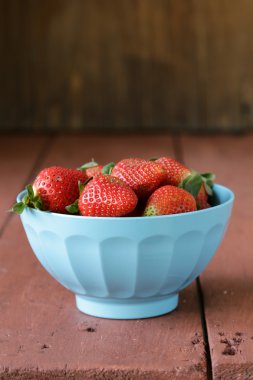 mavi bir kapta sulu olgun çilek