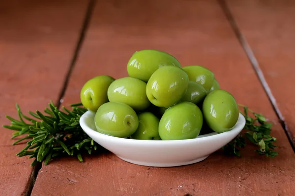 Yeşil Zeytin kase ahşap bir masa üzerinde marine edilmiş. — Stok fotoğraf