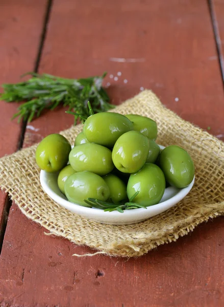 Aceitunas marinado verde en un tazón sobre una mesa de madera — Foto de Stock