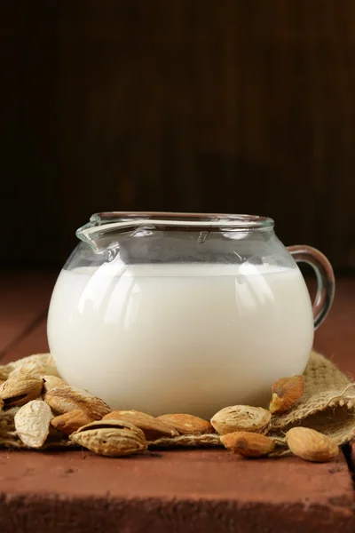 Mandelmilch im Glaskrug mit ganzen Nüssen — Stockfoto