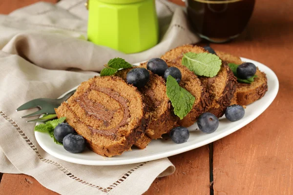 Chocolade biscuit roll gegarneerd met muntblaadjes en bosbessen — Stockfoto