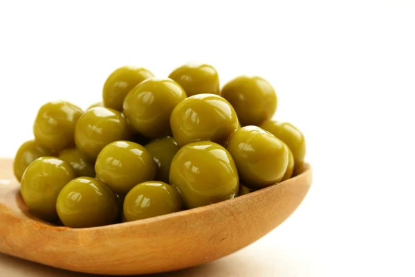 Canned green peas in a wooden spoon — Stock Photo, Image