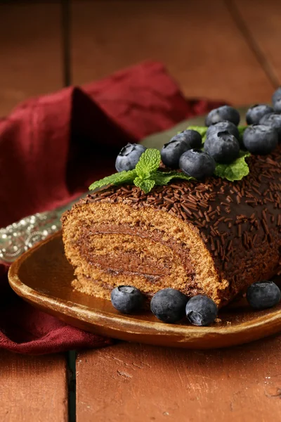 Chocolade biscuit roll gegarneerd met muntblaadjes en bosbessen — Stockfoto