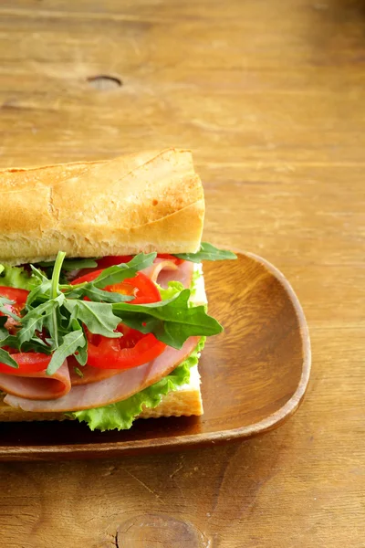 Baguette sandwich with arugula, ham and tomatoes — Stock Photo, Image