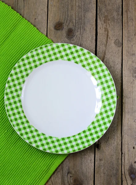 Άδειο πιάτο σε ένα ξύλινο φόντο με πράσινο χαρτοπετσέτας — Φωτογραφία Αρχείου
