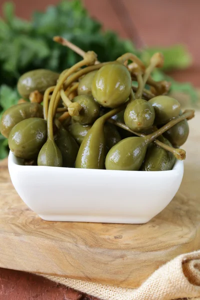 Ingemaakte kappertjes in kom op een houten tafel — Stockfoto