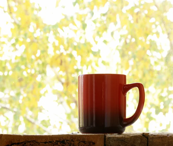 木製のテーブルの秋のウィンドウの背景に赤のマグカップ — ストック写真