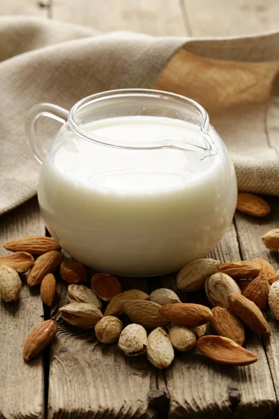 Almond milk in a glass jug with whole nuts — Stock Photo, Image