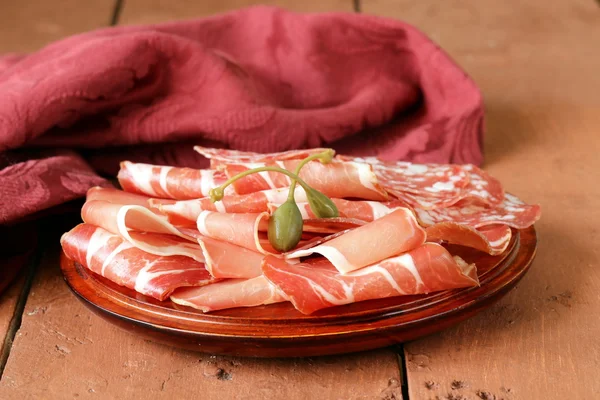 Gesneden gedroogde worstvlees (prosciutto, ham, salami) geserveerd op een houten bord — Stockfoto