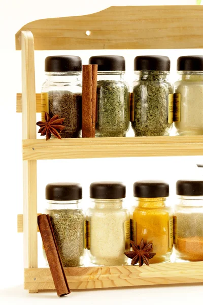Diferentes conjuntos de especias en frascos de vidrio en estante de madera — Foto de Stock