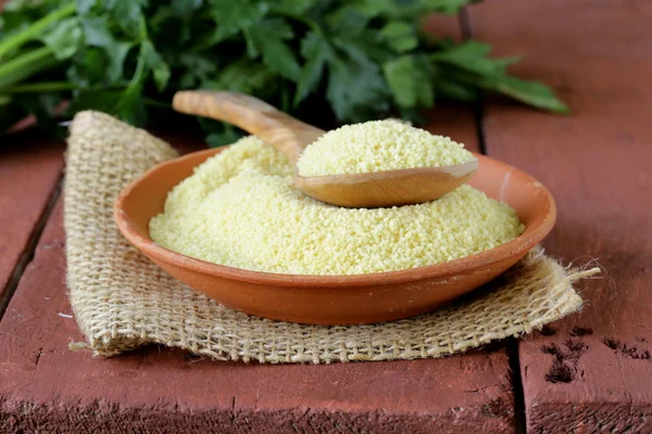 Cereales cous cous en un tazón de barro sobre mesa de madera —  Fotos de Stock