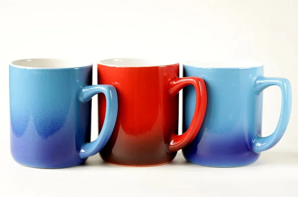 Tre färgglada kaffemuggar (blå, röd) på en vit bakgrund — Stockfoto