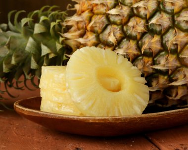 ahşap bir tabağa dilimlenmiş tatlı ananas