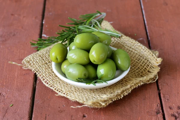 Olive marinate verdi in ciotola su un tavolo di legno — Foto Stock