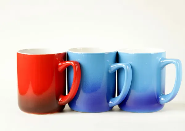 Drie kleurrijke koffiemokken (blauw, rood) op een witte achtergrond — Stockfoto