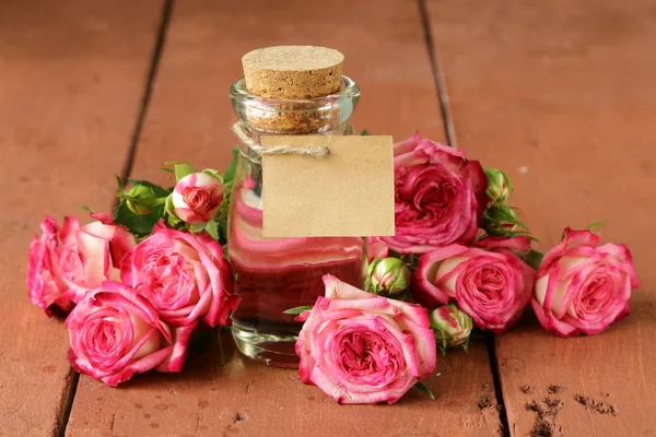 Esencia de flores de rosa en una botella de vidrio —  Fotos de Stock