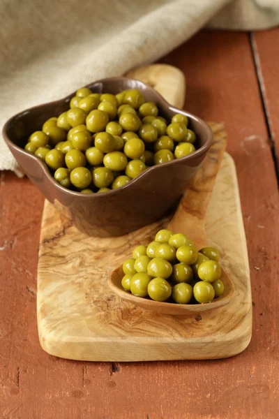 Pois verts en conserve dans une cuillère en bois — Photo