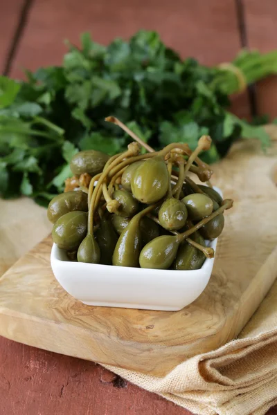 Pickled capers in bowl on a wooden table — Stock Photo, Image