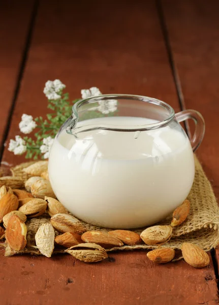 Amandelmelk in een kruik glas met hele noten — Stockfoto