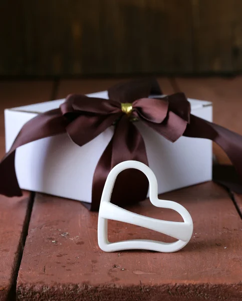 Şerit yay ahşap arka plan üzerinde beyaz hediye kutusu — Stok fotoğraf
