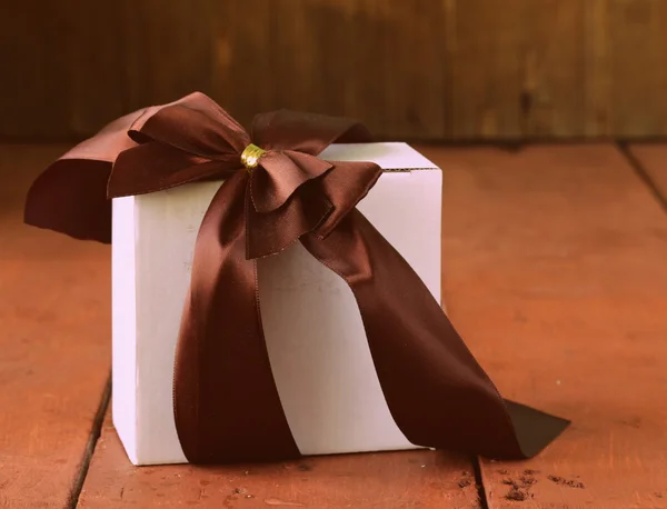在一个木制的背景上的缎带蝴蝶结白色礼品盒 — 图库照片