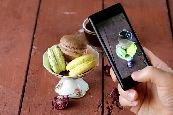 Smartphone strzał włoskich migdałów macaroons przy filiżance espresso — Zdjęcie stockowe