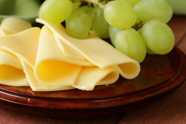 Fromage servi sur une planche de bois avec des raisins verts — Photo