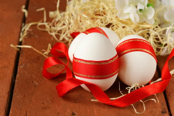 Festive eggs decorated with red ribbon - symbol of Easter holiday — Stock Photo, Image