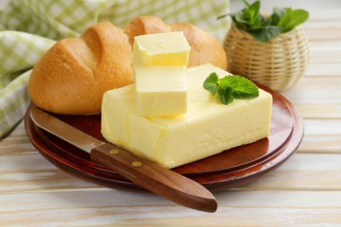 Piece of fresh butter for breakfast on a wooden board clipart