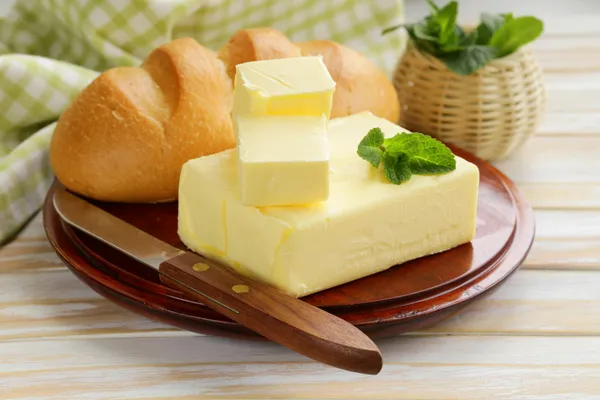 Piece of fresh butter for breakfast on a wooden board — Stock Photo, Image