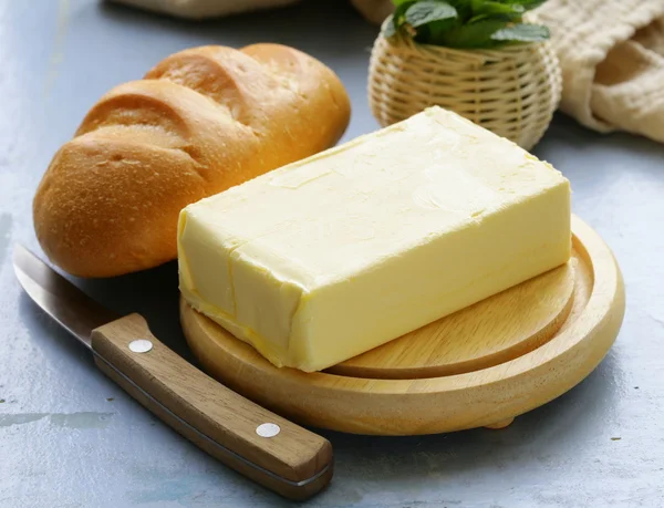 Pièce de beurre frais pour le petit déjeuner sur une planche de bois — Photo