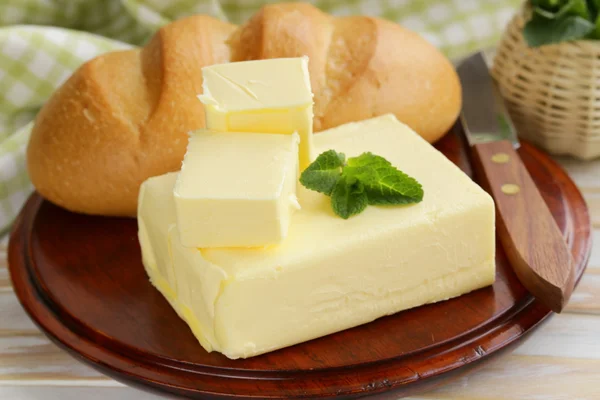 Pedaço de manteiga fresca no café da manhã em uma tábua de madeira — Fotografia de Stock