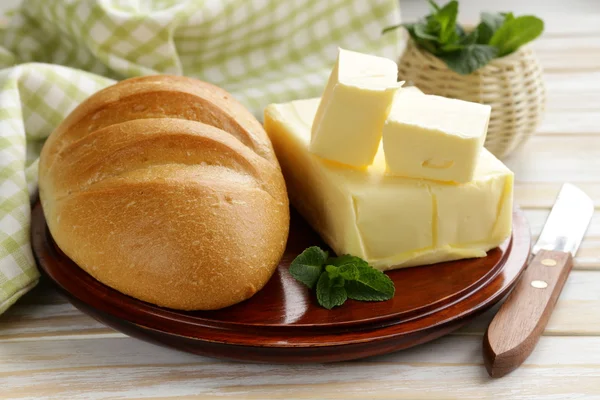 Pièce de beurre frais pour le petit déjeuner sur une planche de bois — Photo