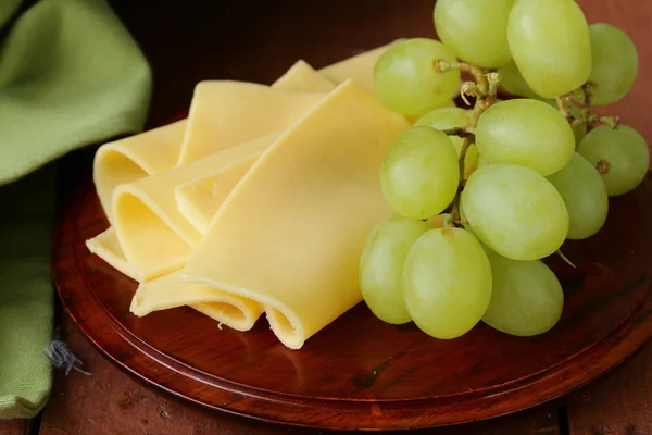 Fromage servi sur une planche de bois avec des raisins verts — Photo