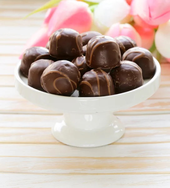 Dulces de chocolate y flores sobre fondo de madera — Foto de Stock