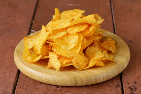 Natural potato chips with paprika in a bowl on a wooden table