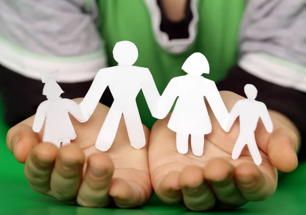 Children 's hands holding a paper human family — стоковое фото