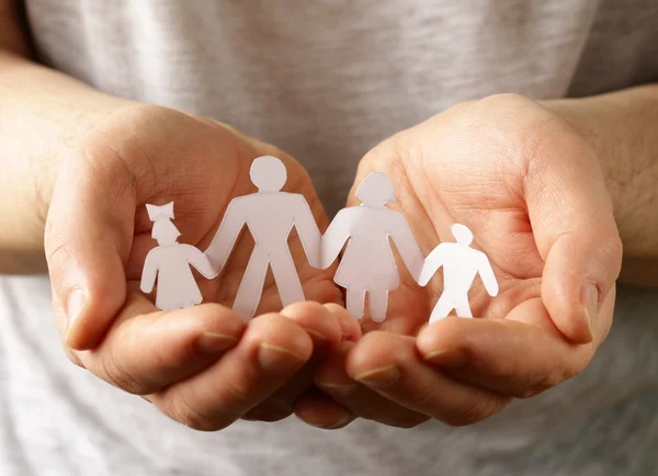 Мужские руки держат бумажную человеческую семью — стоковое фото