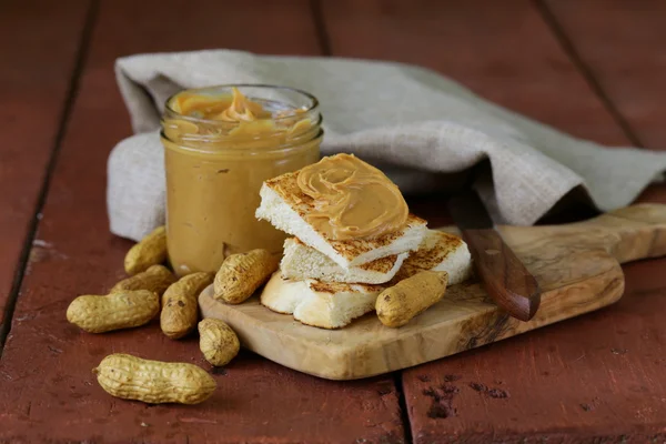 Hausgemachte Erdnussbutter mit ganzen Nüssen auf einem Holztisch — Stockfoto