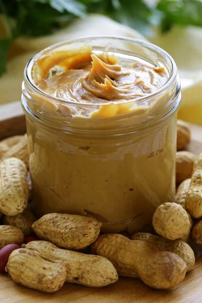 Hausgemachte Erdnussbutter mit ganzen Nüssen auf einem Holztisch — Stockfoto