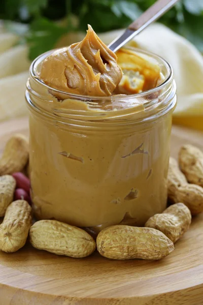 Домашнее арахисовое масло с целыми орехами на деревянном столе — стоковое фото
