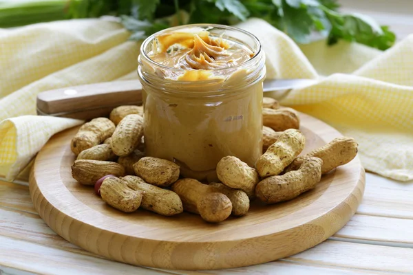 Hausgemachte Erdnussbutter mit ganzen Nüssen auf einem Holztisch — Stockfoto