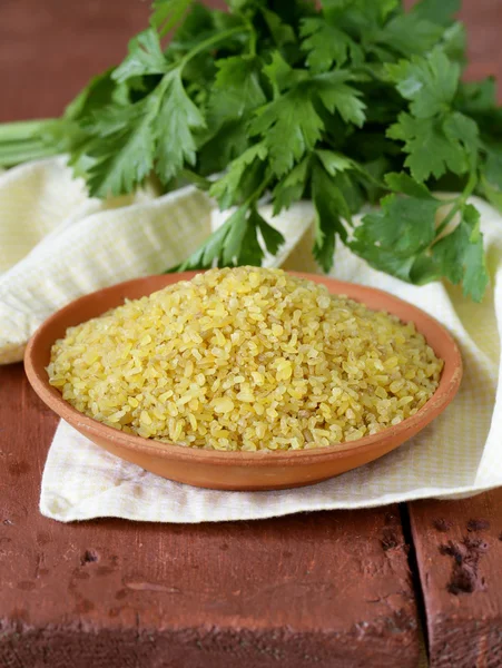 Bulgur in a ceramic bowl on wooden table — Stock Photo, Image