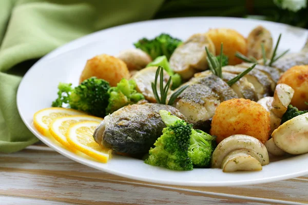 Pesce trota arrosto con verdure e limone su un piatto — Foto Stock